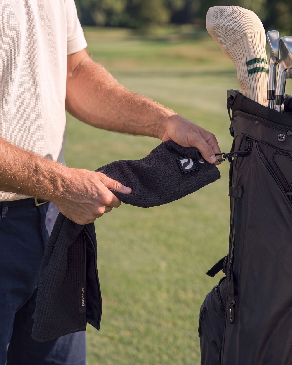 Golfer clipping the towel back onto his golf bag with the screw-lock carabiner