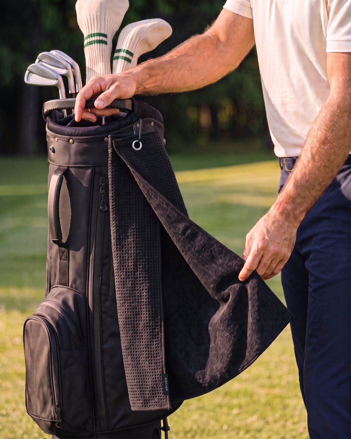 Golfer beside his bag folding back the towel to show the waffle face and the terry face