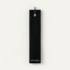 Black Dryven golf towel folded in thirds with screw-lock carabiner, magnetic logo badge and cream wordmark.