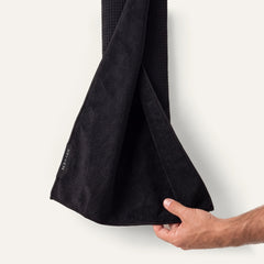 A hand holds open the black Dryven golf towel to show its waffle-weave and terry faces.