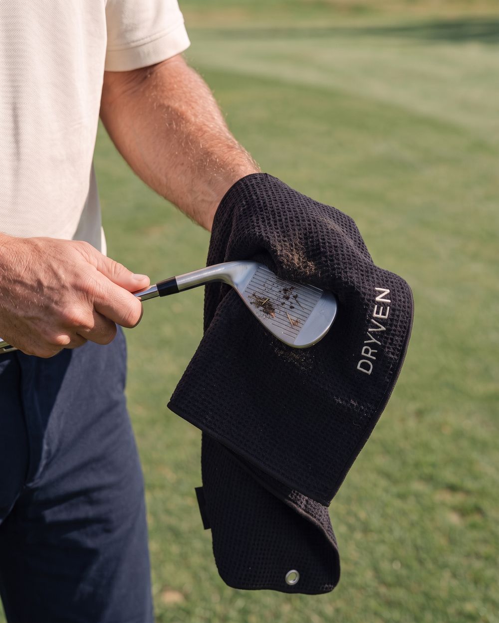 Golfer wiping dirt from the grooves of a wedge with the waffle face